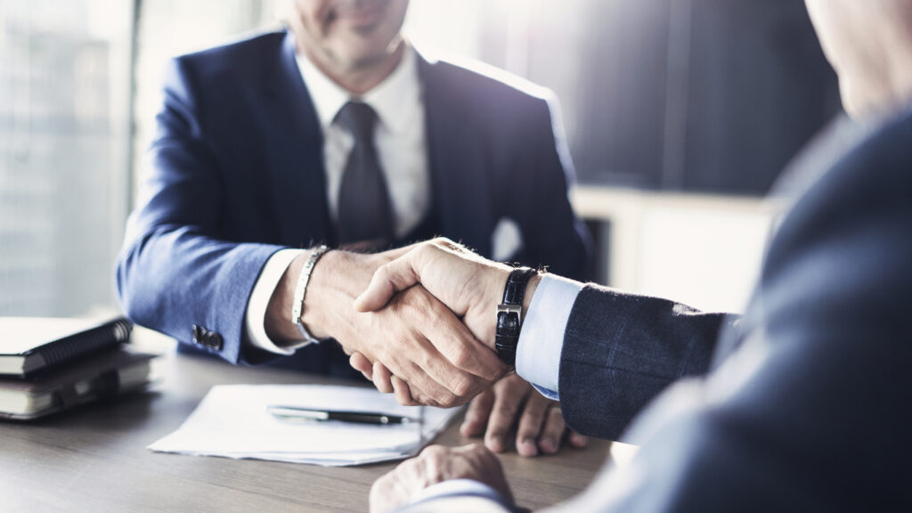 Businessmen shaking hands in an agreement during a meeting.